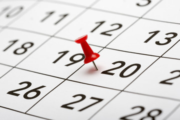 Pin on the date number 20. The twentieth day of the month is marked with a red thumbtack. Focus point on the red pin.