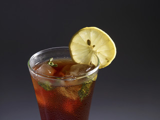 A GLASS OF ICE TEA WITH LEMON SLICE ON DARK BACKGROUND