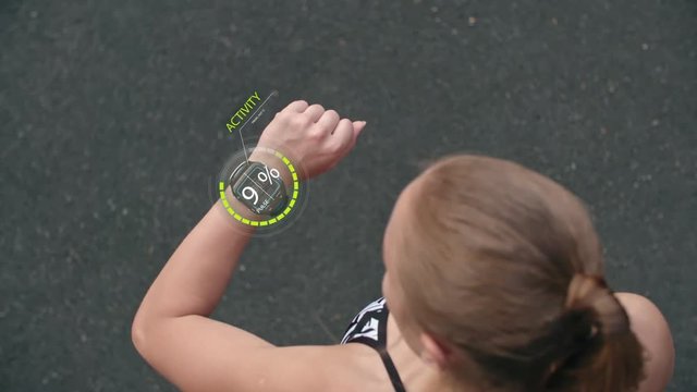 Directly above view of sportswoman using electronic smart watches with animated holographic data and running