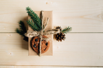 Christmas gift box is packed in kraft paper. Christmas gift decorated: fir sprigs, cookies and pine cone. Christmas concept.