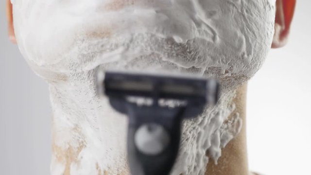Man shaving with foam and manual razer. Close up.
