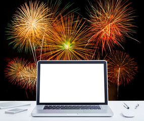 White screen laptop computer on office table with fireworks back