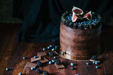 Chocolate cake with fresh blueberry, blackberry and figs on dark rustic background