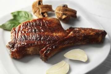Grilled meat with mushrooms and garlic on plate on white wooden table