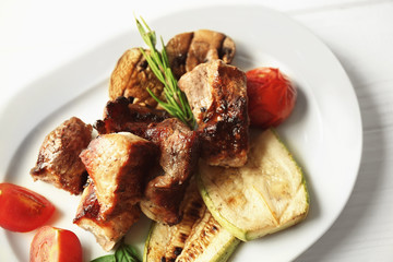 Grilled meat with vegetables on plate, closeup