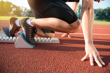 Male athlete on starting position at athletics running track.