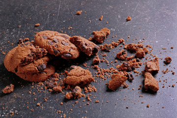 Tasty cookies with chocolate chips and crumbs on dark background