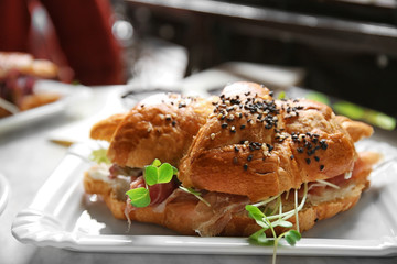 Tasty croissant sandwich on table