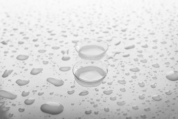Pair of contact lenses and liquid drops on light background, close up view. Medicine and vision concept