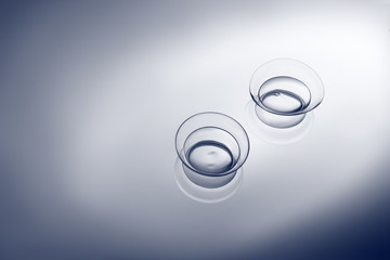Fototapeta premium Pair of contact lenses on smooth light background, close up view. Medicine and vision concept