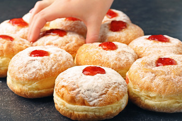 Female hand taking tasty donut from dark table. Hanukkah celebration concept