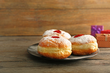 Plate with tasty donuts on wooden background. Hanukkah celebration concept