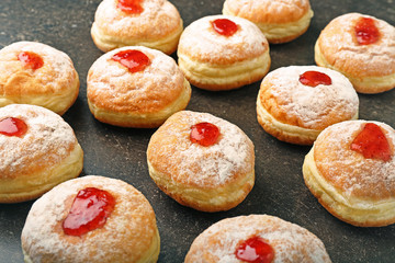 Tasty donuts with jam on dark table. Hanukkah celebration concept