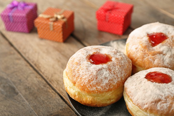 Plate with tasty donuts on wooden background, close up. Hanukkah celebration concept