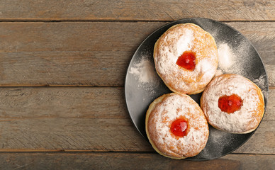 Plate with tasty donuts on wooden background. Hanukkah celebration concept