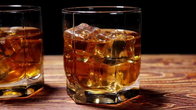 glasses of malt whiskey on a wooden table. video dolly
