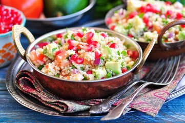 Healthy salad with couscous, tomato, avocado, red onion, pomegranate and olive oil. Eastern cuisine.