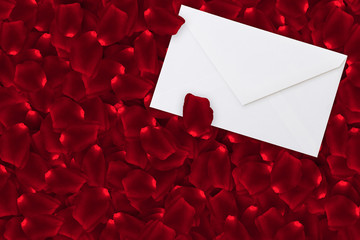 a sea of red rose petals around white love letter envelope with copy space, valentines day concept
