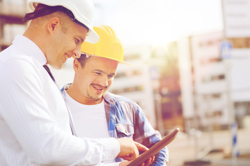 smiling builders in hardhats with tablet pc