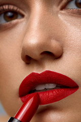 Makeup And Cosmetics. Woman Face With Red Lips Putting Lipstick
