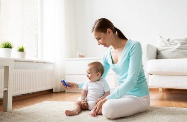 happy mother showing smartphone to baby at home
