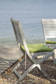Two wooden white chairs on the beash with green pillow