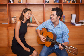 Man Singing and Playing Guitar for Smiling Woman