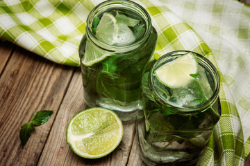 Mojito cocktail with lime and mint in glasses on wooden  background