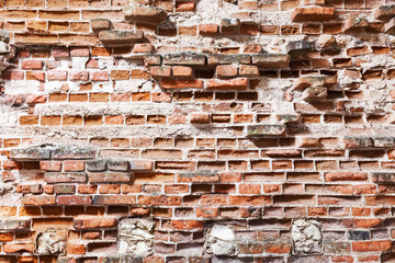 Old damaged red brick wall with cracks