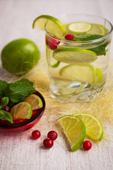 Refreshing drink with lime, mint and cranberries on a light background
