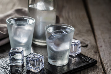 Vodka in shot glasses on rustic wood background