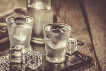 Vodka in shot glasses on rustic wood background
