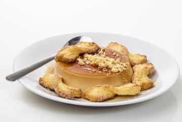 crem caramel con biscotti su piatto con cuchiaino