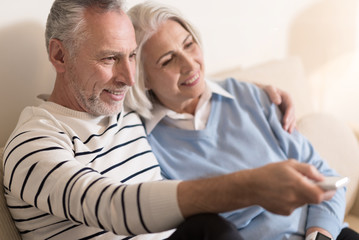 Happy aged couple watching television together