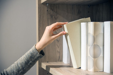 young woman searching for a book in bookstore. student selecting