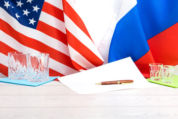 American and Russian flags on agreement table with pen and signing papers  - Political concept of peace cooperation and business between world powerful countries - White copy space