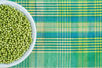 Fresh green peas in a ceramic bowl on table.