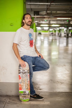 Skateboarder resting against the wall in the underground garage