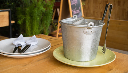 Ice bucket on wood table in restaurant.