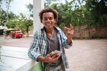 Obraz premium Happy african young man listening to music from cell phone