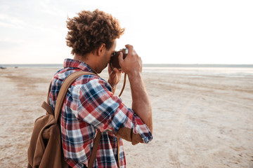 Fototapeta premium African man with backpack taking pictures on the beach