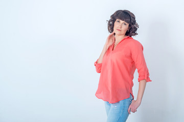 Beautiful young fashionable woman standing in front of a white wall.