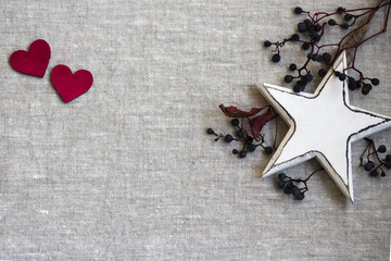 2 rote Herzen mit weissem Holzstern und Beeren vom Wilden Wein auf hellem Leinen