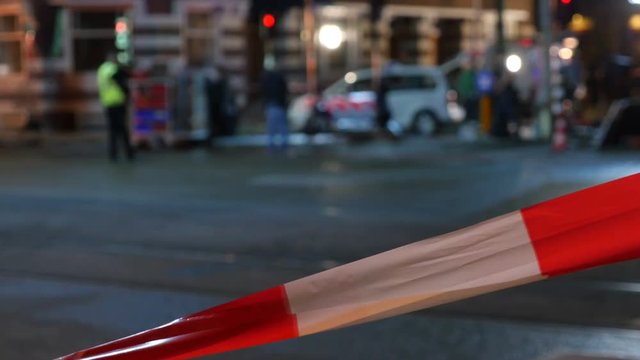 Urban crime scene at night with police cordon.