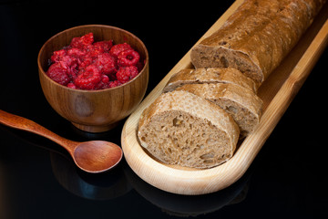 Top view to plate with  sliced bread, cup with raspberries and s