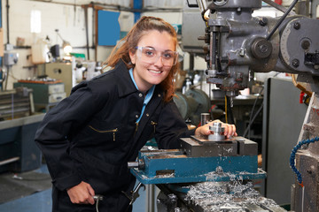 Female Apprentice Engineer Working On Drill In Factory