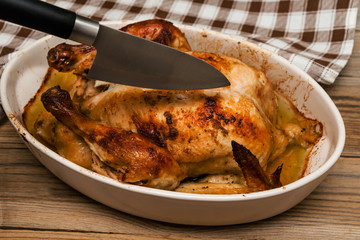Roasted chicken  and knife on wooden table. Selective focus