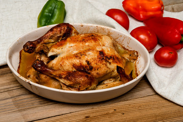 roasted chicken with a golden crust with vegetables on a wooden table