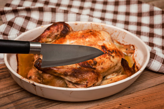 Roasted chicken  and knife on wooden table. Selective focus