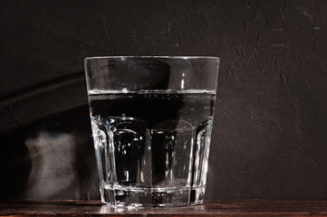 glass of clear water on the wooden textural background